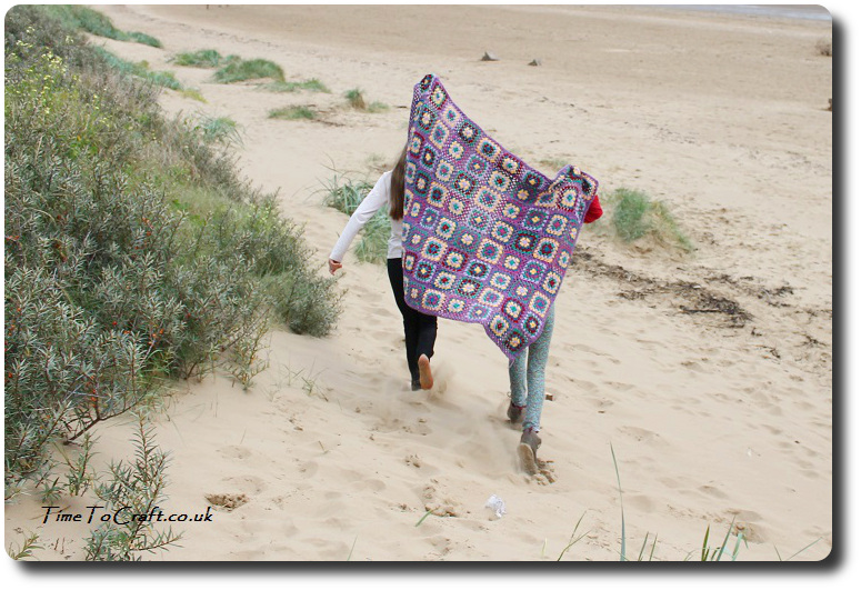 sisters running on the beach with crochet blanket