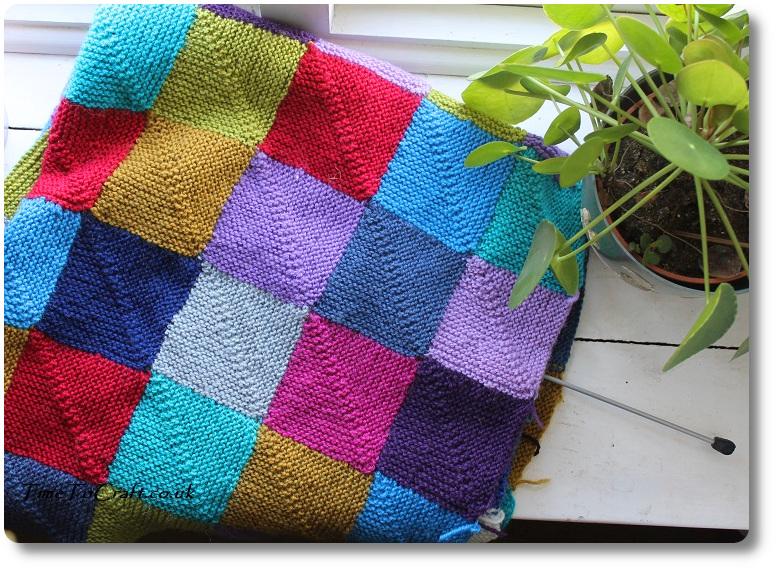 Folded knitted blanket next to plant