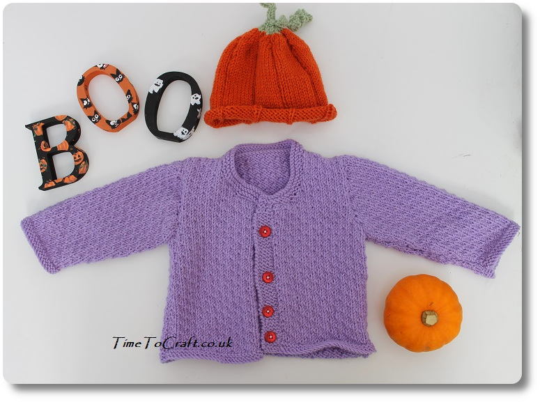 laid out baby cardigan and pumpkin hat